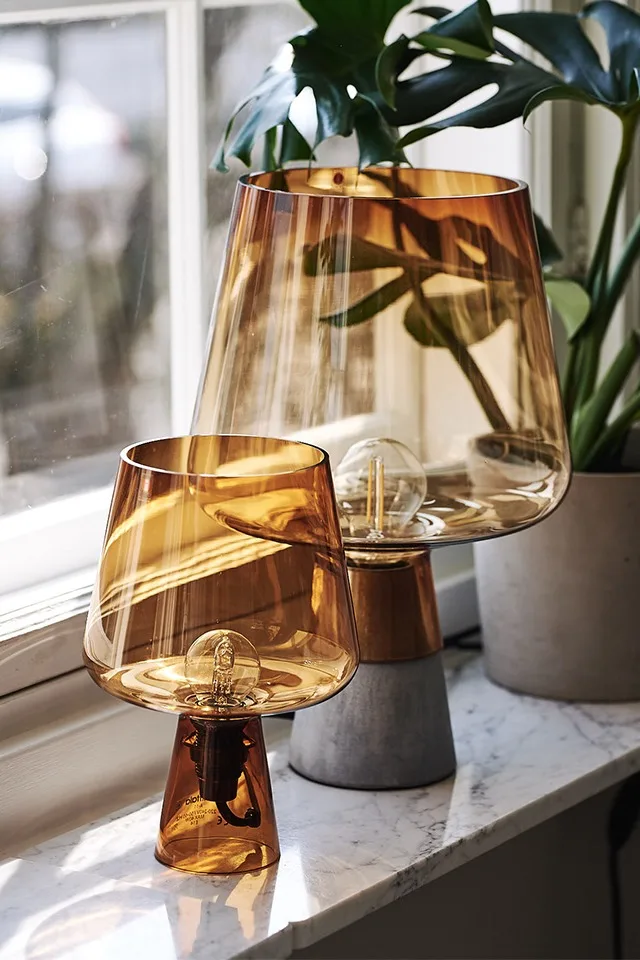 Leimu bordslampa från Iittala i orange färg lyser upp fönsterbrädan i sann nordisk inredningsstil.