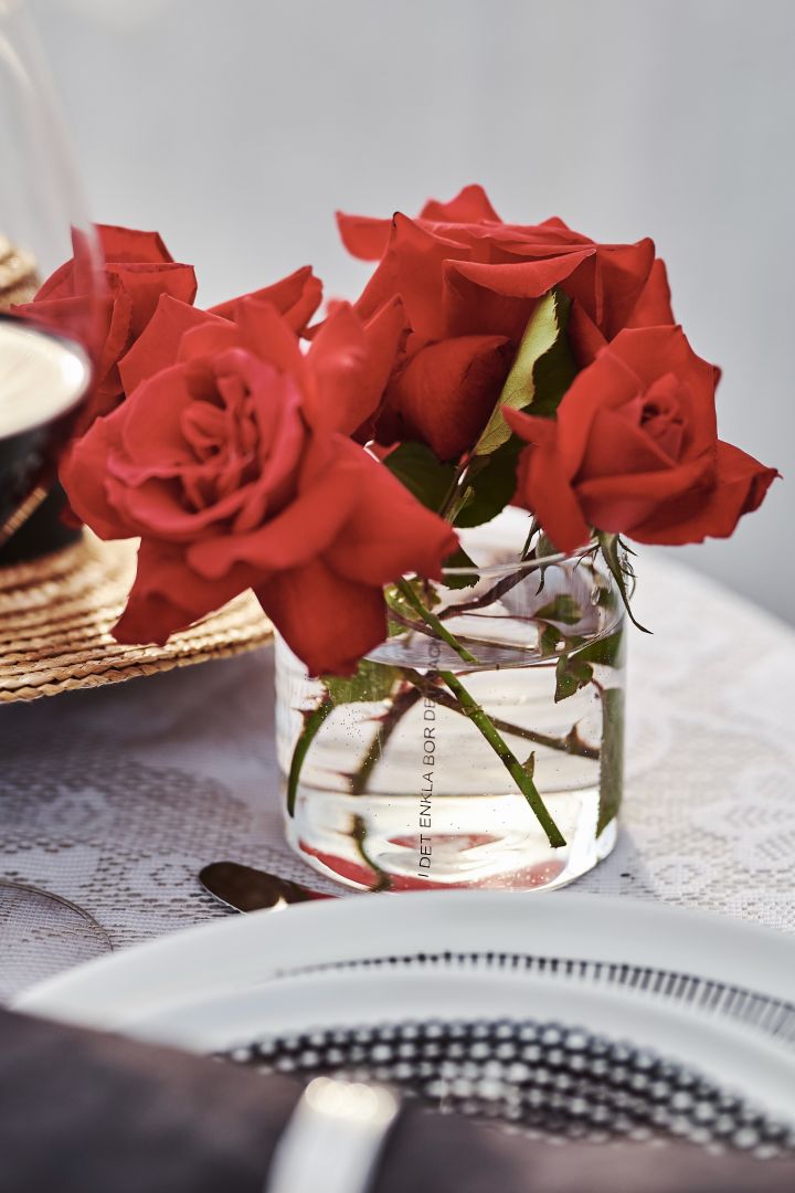Röda rosor huserar i Ernst ljuslykta på romantisk dukning. 