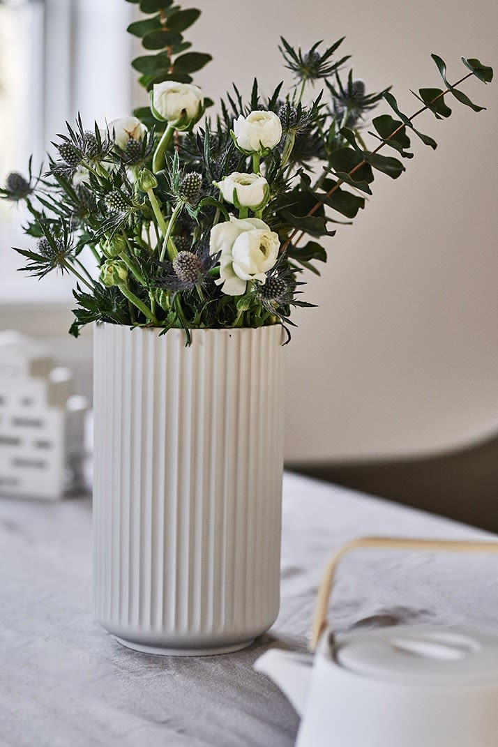 Vårbuketten huserar i en stor vit Lyngby vas på bordet i en matplats inredd i skandinavisk stil. 