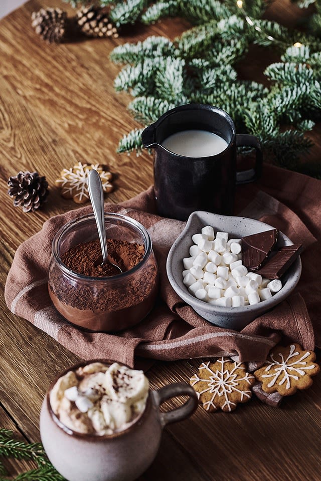 Adventsmys med varm choklad och dess ingredienser som kakao, mjölk och minimarshmallows står bredvid i skålar. 