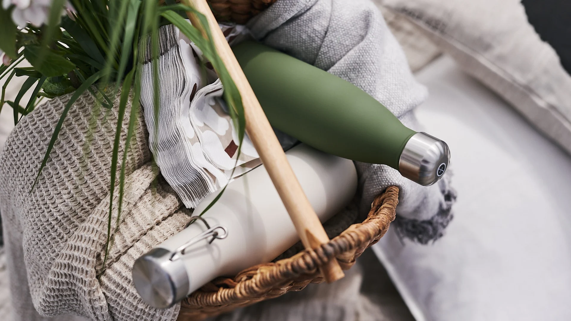 En picknickkorg fylld med servetter, plädar & termosflaskor redo att tas med för picknick på stranden. 