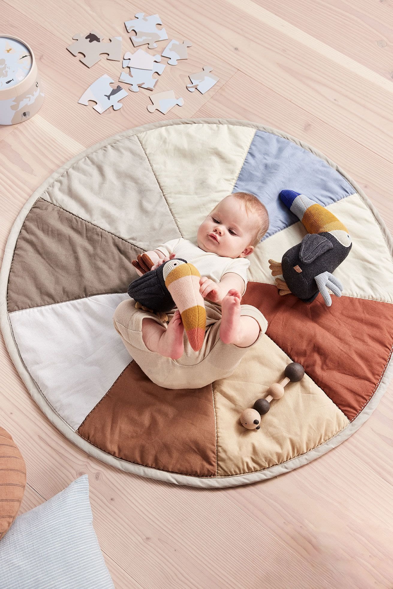 Gosedjuret Trine Toucan från OYOY ligger bredvid en bebis på babyfilten Moni. Gosedjuret är tillverkat helt av återvunnet material, vilket gör det inte bara till en användbar leksak utan också till en hållbar present till babyshower.