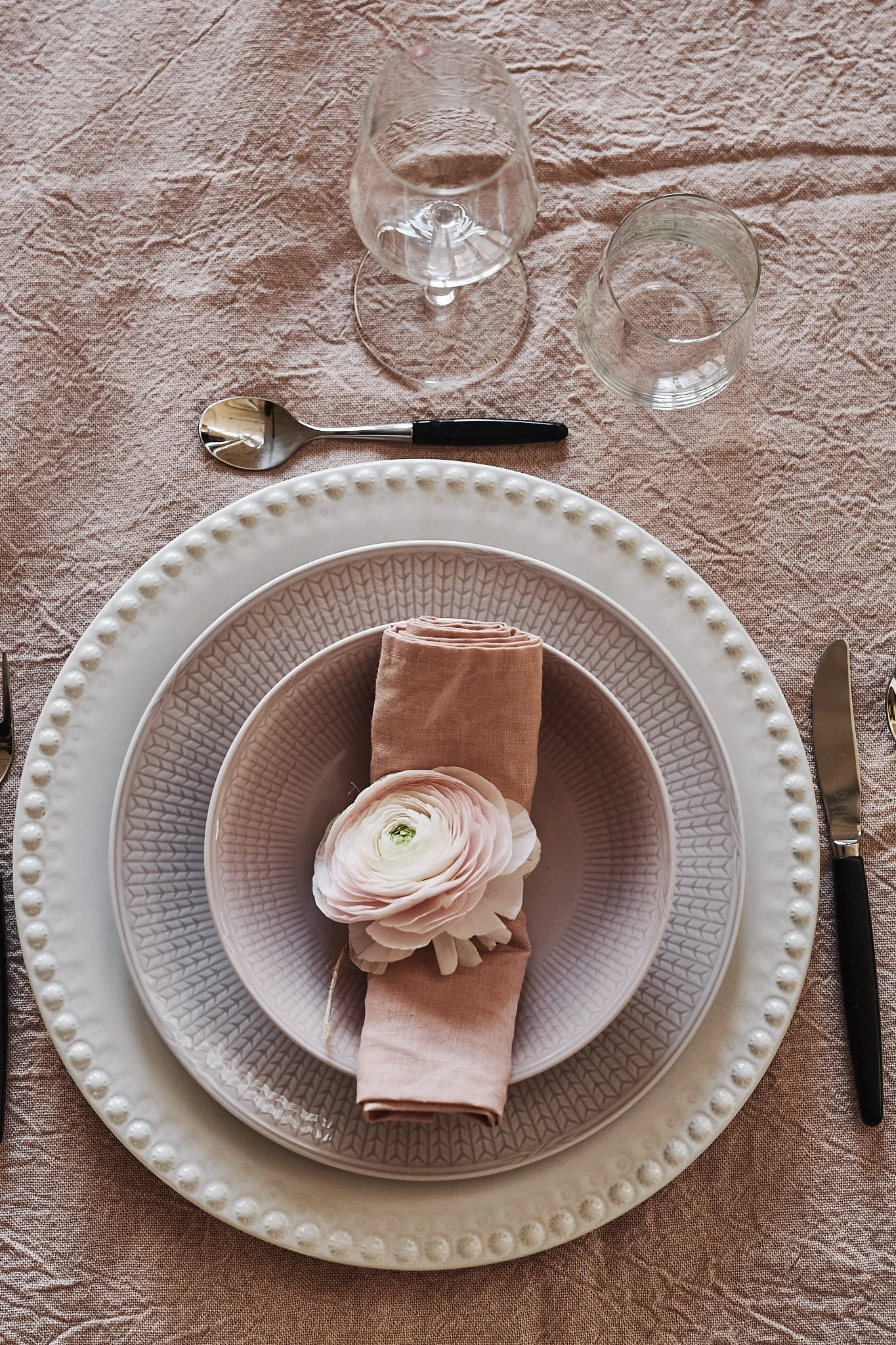 En rosa sommardukning där servisen Swedish Grace i rosa mixats med vit undertallrik från PotteryJo.