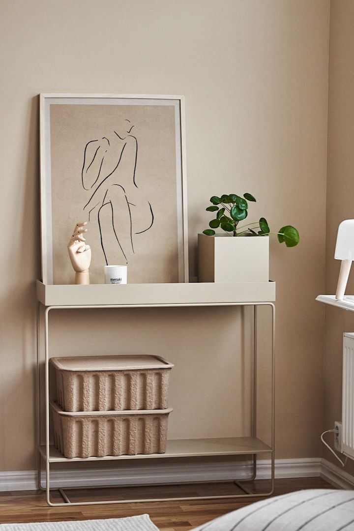 Inred ditt vardagsrum med beige inredning ton-i-ton för att skapa ett stilrent intryck i ditt hem. Här ser du mångsidiga Plant Box konsolbord från Ferm Living tillsammans med förvaringslådor och Paper Collective Grace poster.