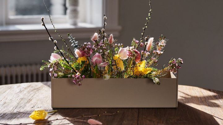 Liten beige Plant Box från Ferm Livingstår på bordet med vårblommor i för inredningsinspiration till våren. 