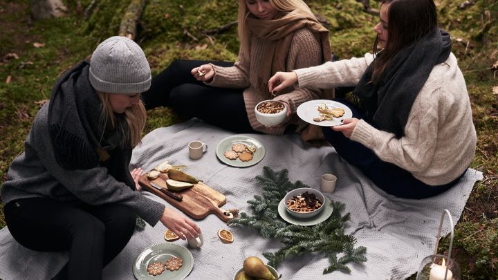 Ett annorlunda glöggmingel i skogen där sällskapet sitter på marken och dricker glögg och äter pepparkakor. 