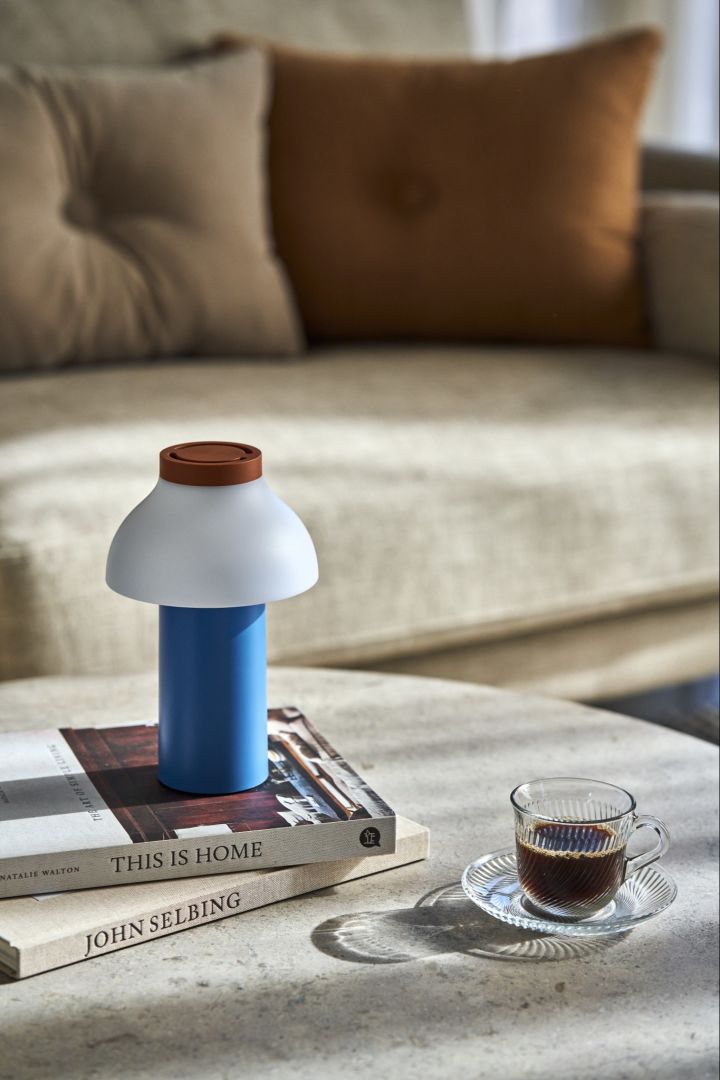 Lekfulla PC Portable bordslampa i blått, vitt och brunt bredvid trendiga Pirouette kopp med fat i klarglas från HAY.