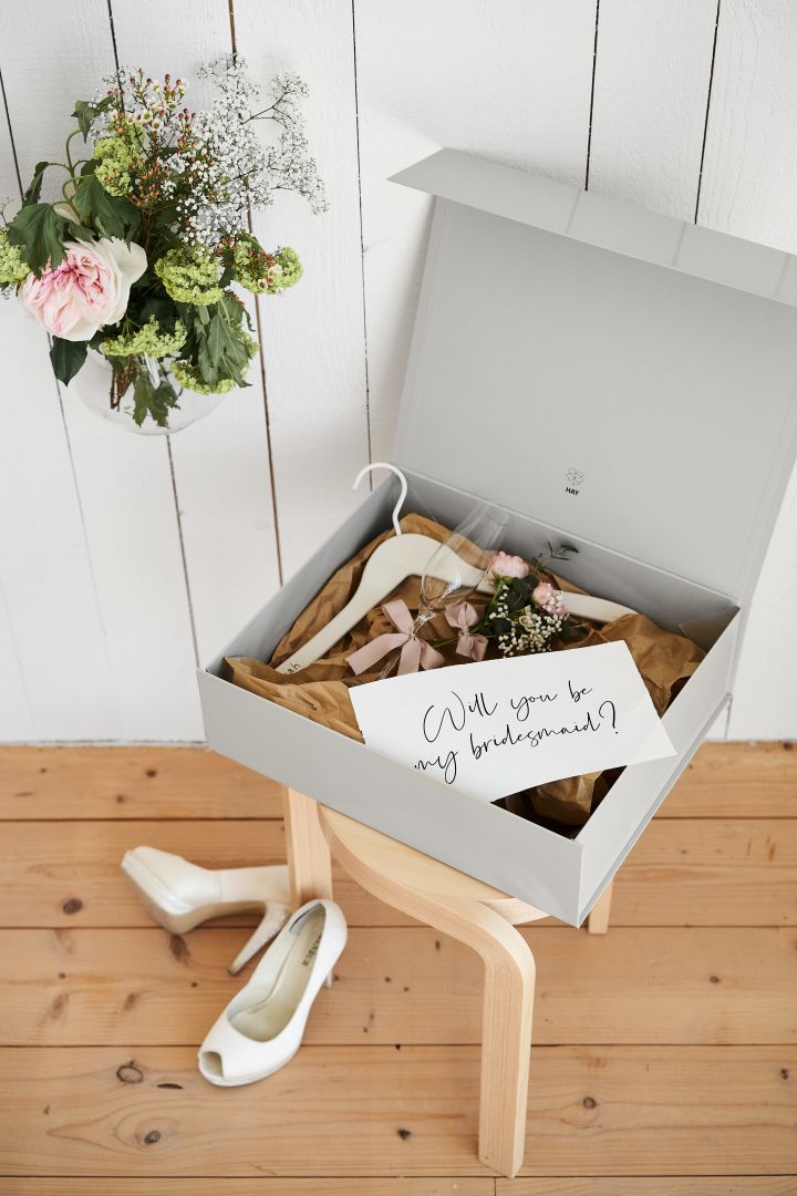 Bröllop - tips inför all bröllopsplanering är att "fria" till din brudtärna med en box fylld av fina saker. Här en grå låda från HAY med blommor och en galge med namn på. 