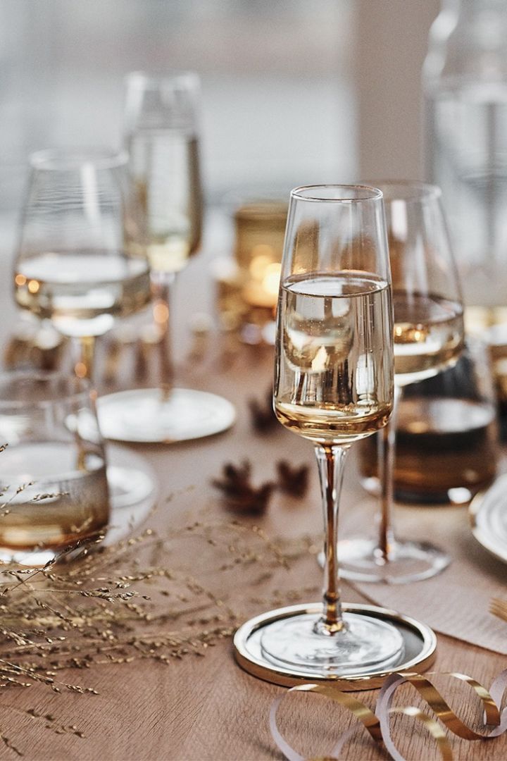 Bärnstensfärgat champagneglas från Broste Copenhagen förgyller en nyårsdukning i guld. 