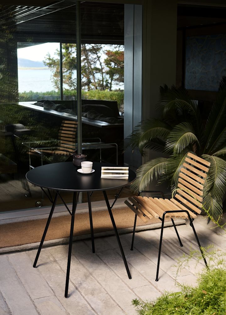 RFH RD4 patio side chair från &Tradition står på en uteplats med ett runt bord.