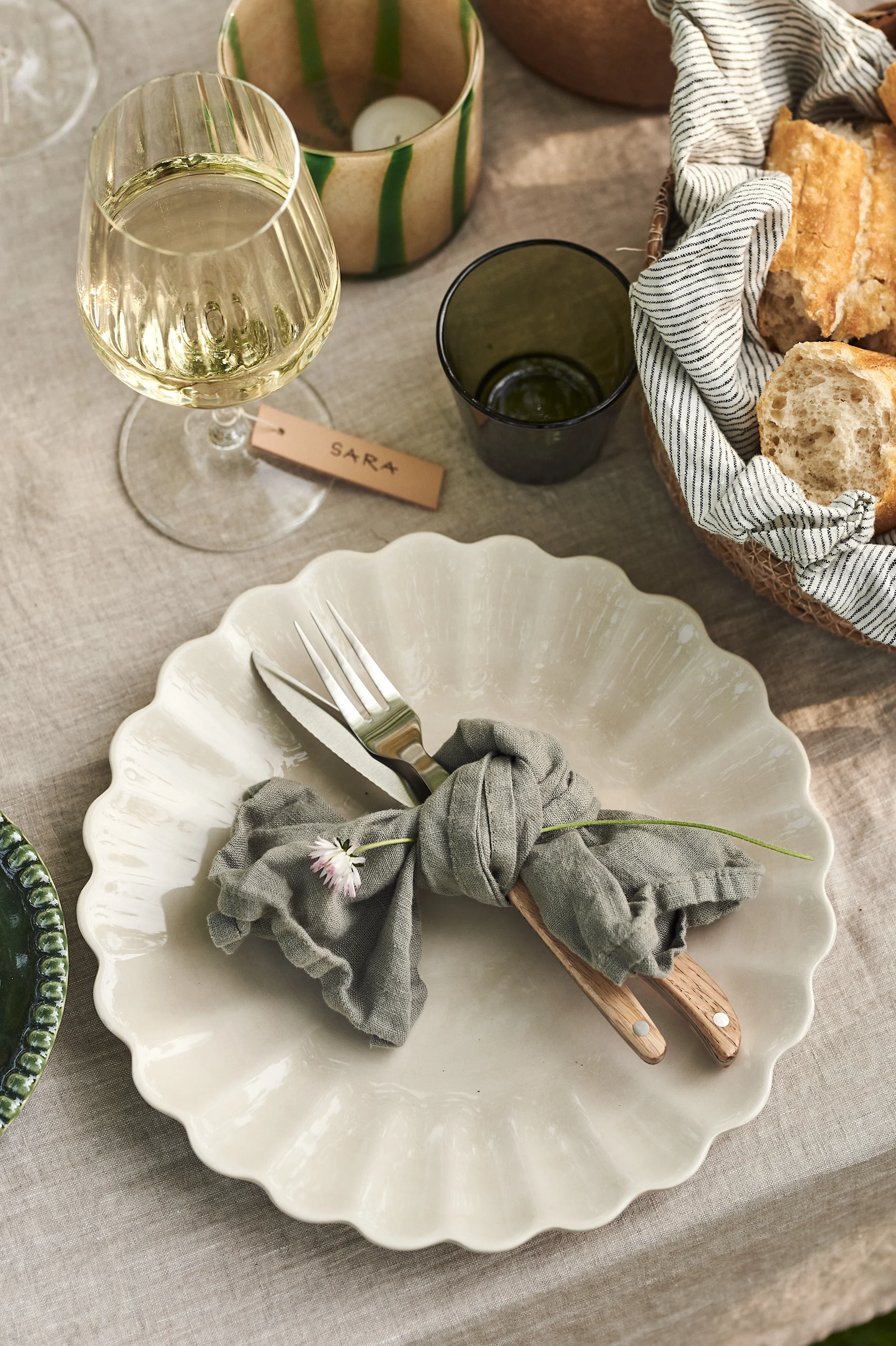En sommardukning i trädgården är inte komplett utan en fin knyten grön linneservett från Himla med en blomma i på Oyster assiett från Mateus i färgen Sand.