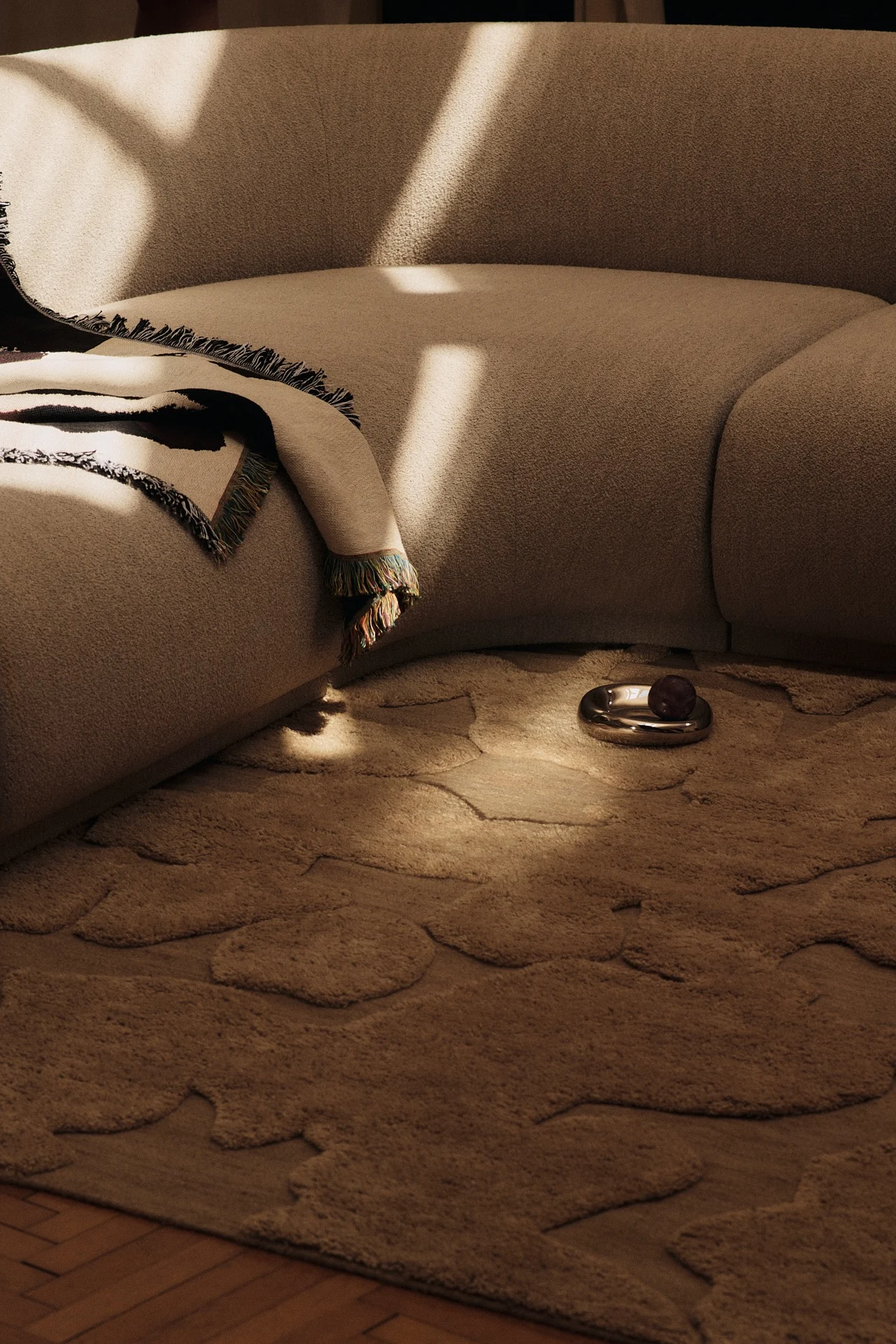 Färgtrenderna 2026 kommer till uttryck i detta vardagsrum, där ljusbrun inredning kombineras med en 60-talsinspirerad mönstrad matta i kombucha nyans.