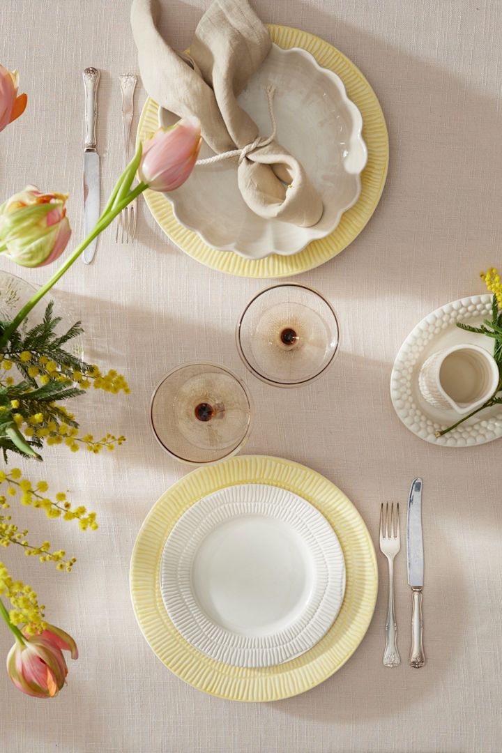 En färgglad bordsdekoration till påsk, bestående av Stripes-tallrikar från Mateus, glas från Byon och servetter från Scandi Living.