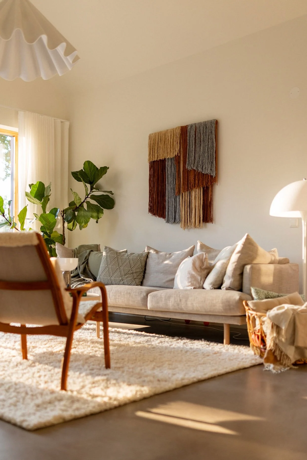 Tham väggdekoration i textil från Tinted hänger på en vägg i ett vardagsrum över en soffa. 