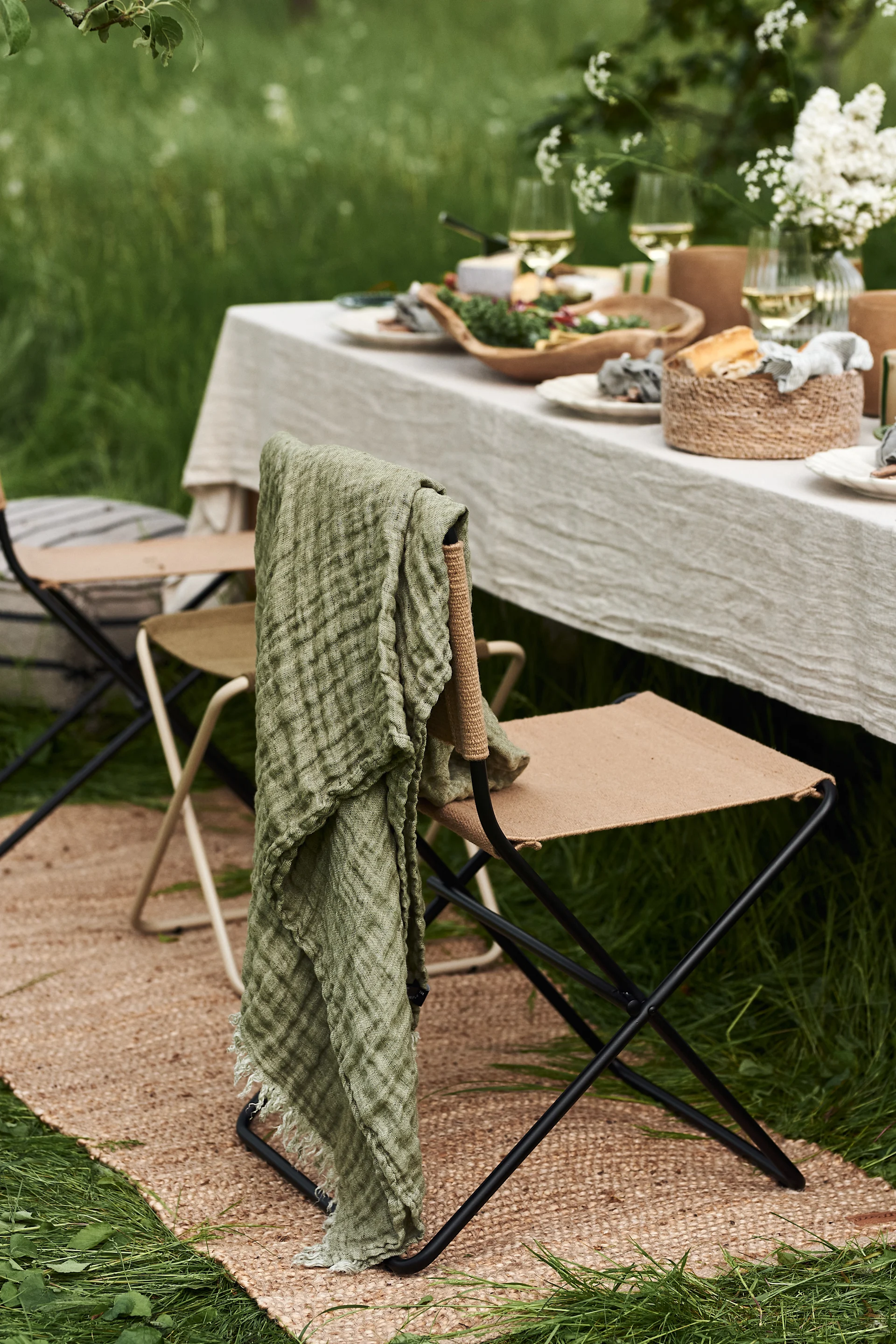 En sommardukning i trädgården blir inte komplett utan mjuka textilier såsom denna fina Hannelin pläd i grönt från Himla som blir en fin detalj över stolsryggen.