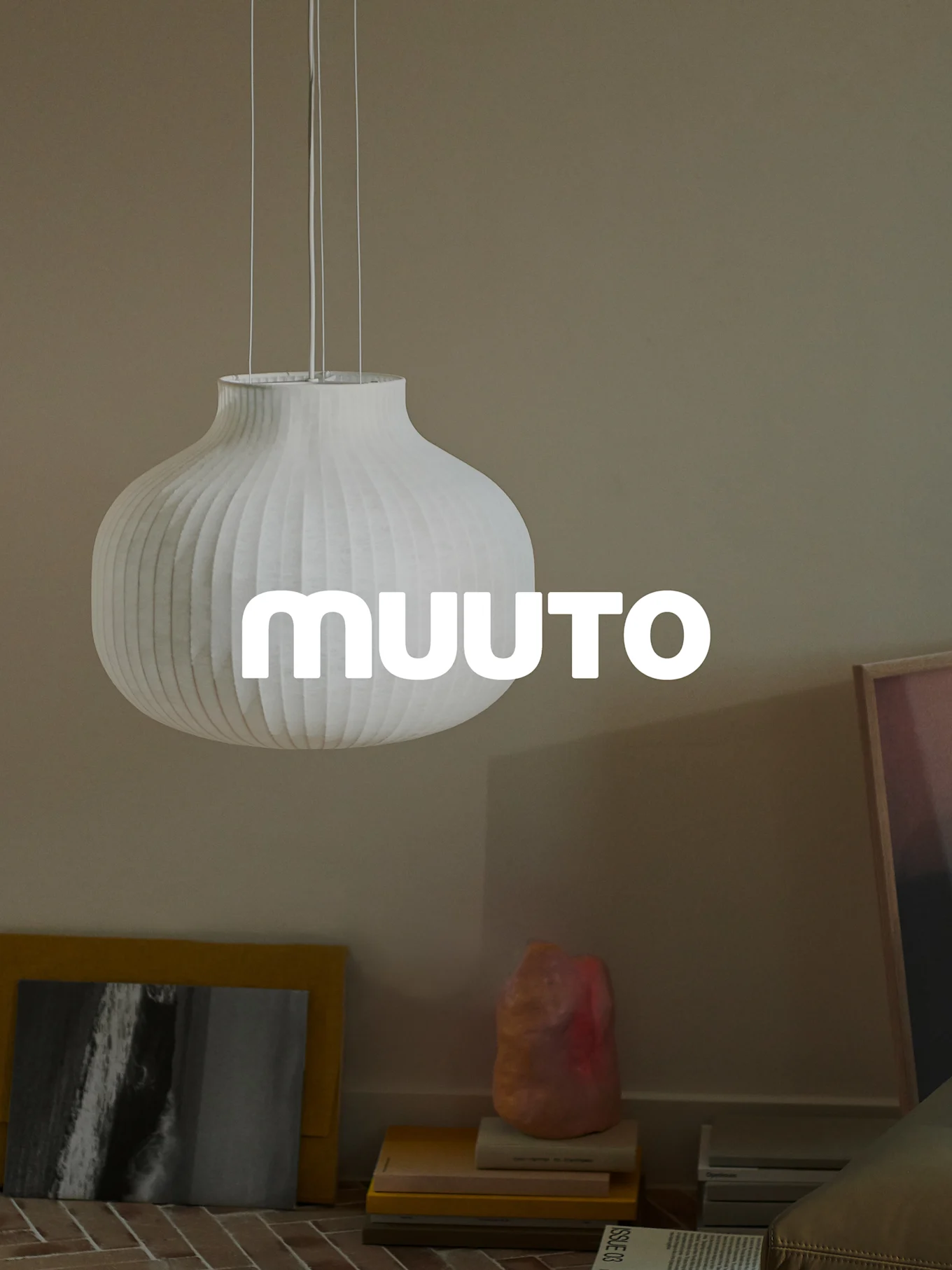 Vit räfflad, kalebassformad taklampa med 'MUUUTO'-logotyp i ett beige rum.