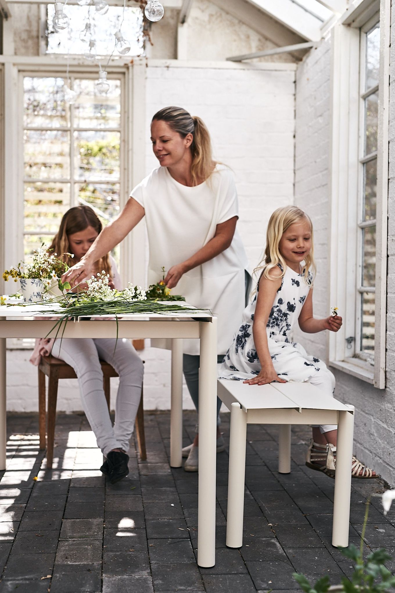 Familjen binder midsommarkrans i växthuset och Linear stålbord från Muuto passar perfekt för ändamålet. 