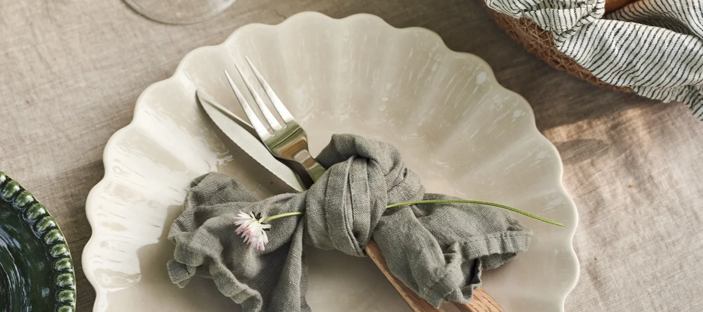 Duka till midsommar - här beigt Mateus-porslin, en knuten servett och bestick.