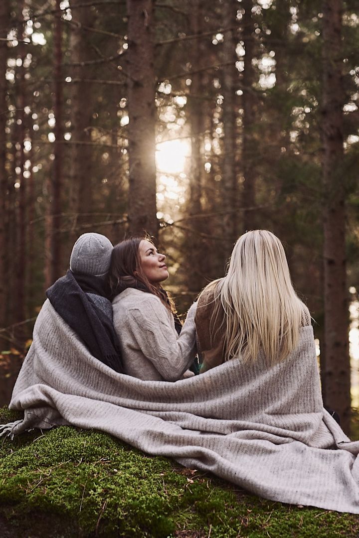 Beige Ralph ullpläd från Klippan Yllefabrik värmer väninnorna på deras annorlunda glöggmingel i skogen. 