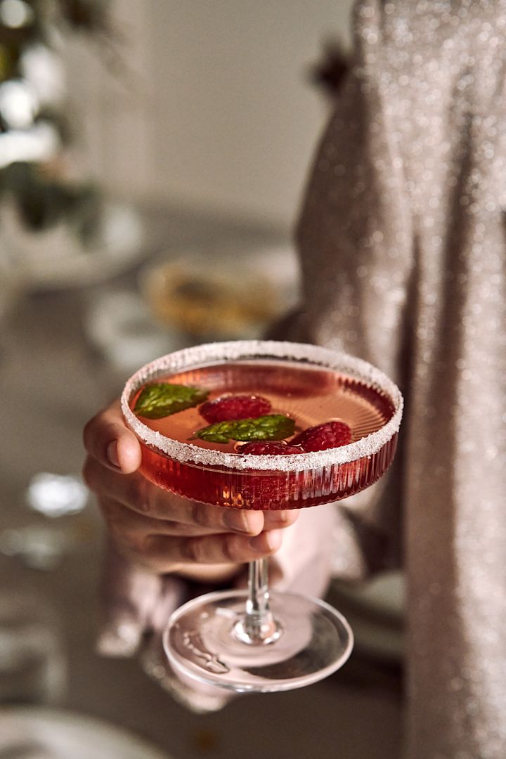 Gör trerätters middag till årets nyårsdukning 2022. Här ser du en festlig hallondrink som serveras i Ripple champagneglas från ferm LIVING.