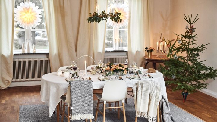En vit, modern juldukning med Snöblomma adventsstjärna i fönstret och Form chair-stolar runt bordet.