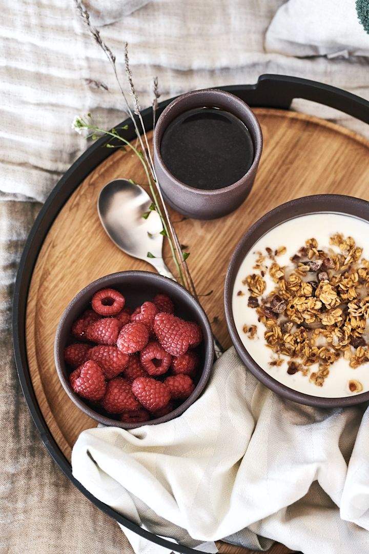 Frukost på sängen serveras på vacker bricka från Eva Solo med bär och müsli ur bruna skålar från Ferm Living. 