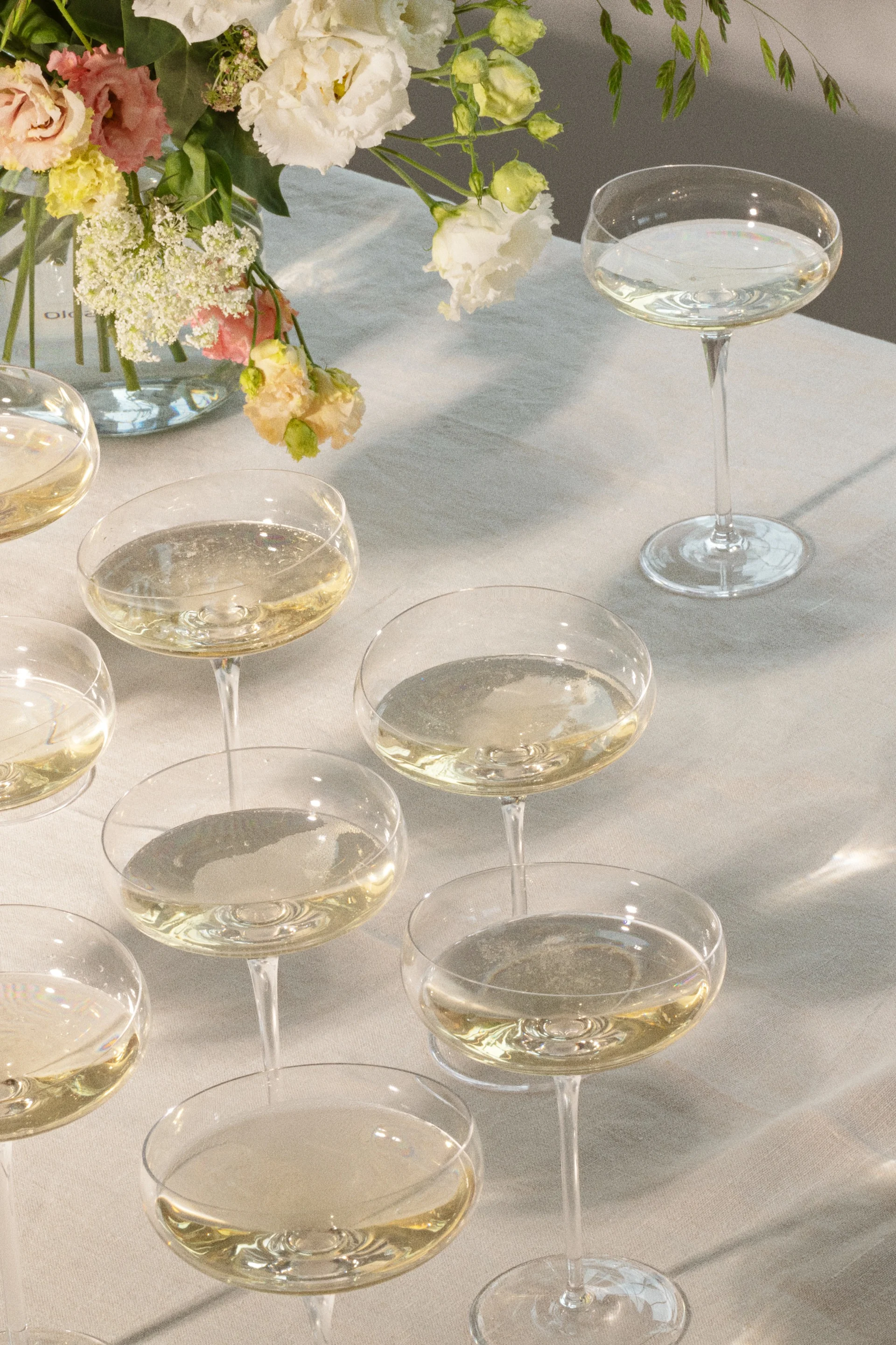 Champagneglas med mousserande drycker på ett bord med blomsterarrangemang.