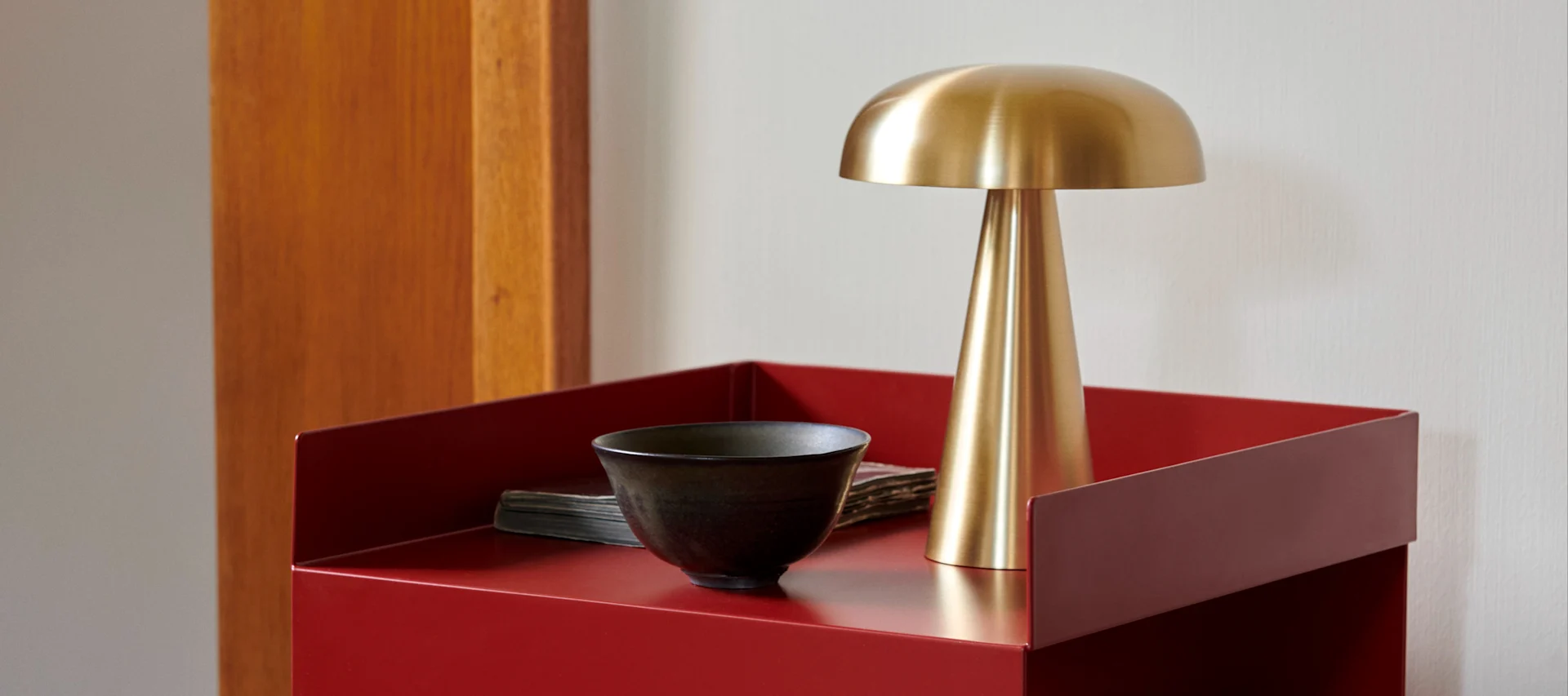 Guldig lampa på ett rött bord med raka linjer och klara färger.