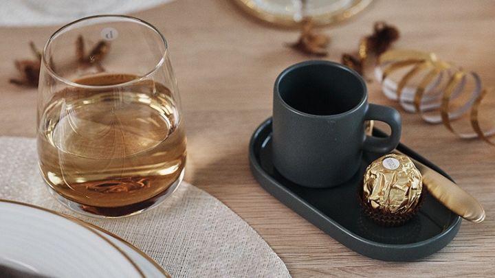 Mio kaffemugg och choklad i guldpapper vilar på bordet i väntan på tolvslaget på en nyårsdukning i guld. 
