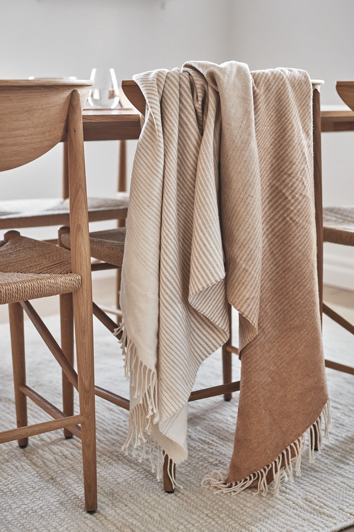 Scandi Living pläd i bomull som skiftar mellan olika toner i beige som hänger över &Tradition Drawn stol - en av 7 beigea favoriter att satsa på i höst.