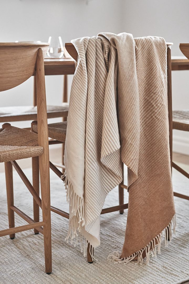 Scandi Living pläd i bomull som skiftar mellan olika toner i beige som hänger över &Tradition Drawn stol - en av 7 beigea favoriter att satsa på i höst.