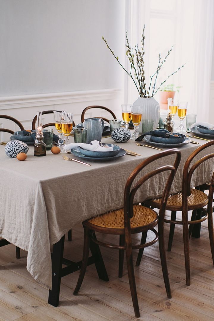 En elegant men samtidigt rustik påskdukning med ägg på bordet, blått porslin, och påskris i hög vas är ett sätt att duka i påsk. 