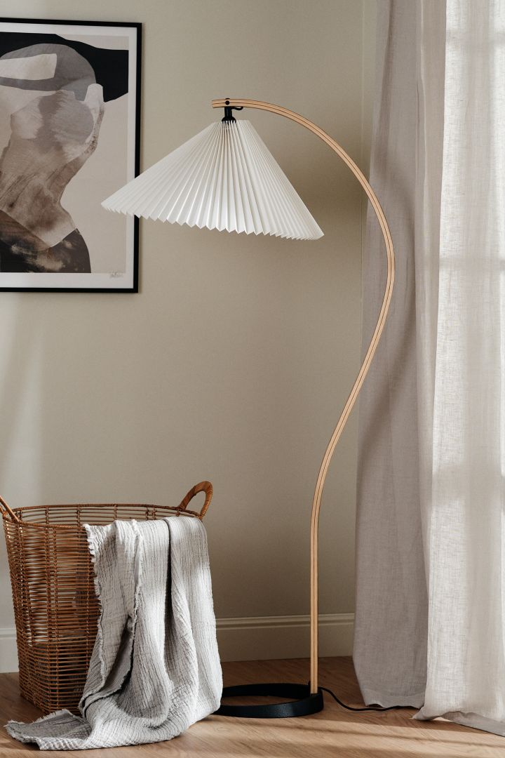 Timberline golvlampa från Gubi är ett tips på en trendig lampa med plisserad lampskärm, den har en böjd träarm i ek och passar perfekt att ha i vardagsrummet.