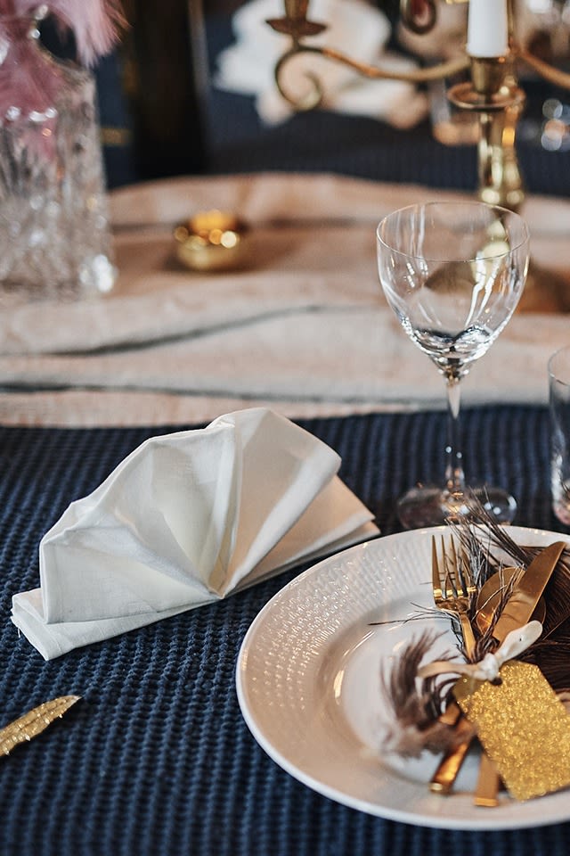 Clean linneservett i vitt från Nordic Nest vikt som en klassisk solfjäder, perfekt för den festliga nyårsdukningen!