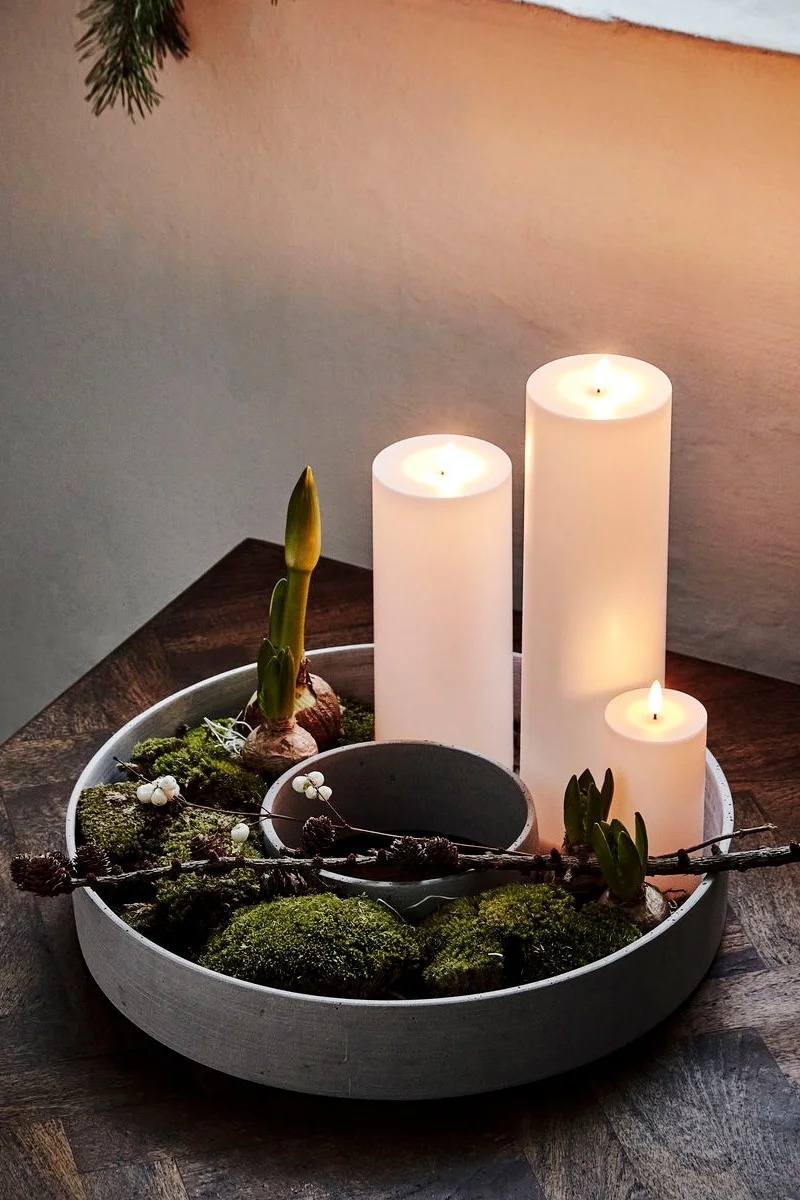 En mångsidig adventsjusstake som är rund ioch fylld med grönska. 