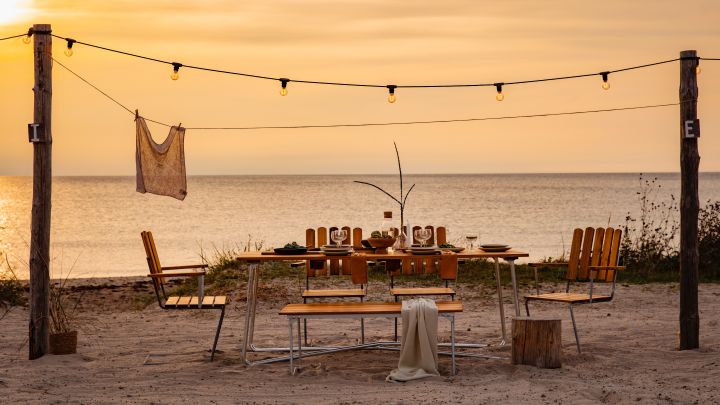 Lär känna Grythyttan Stålmöbler, här A2 stolar och A1 bord på strand vid solnedgång.