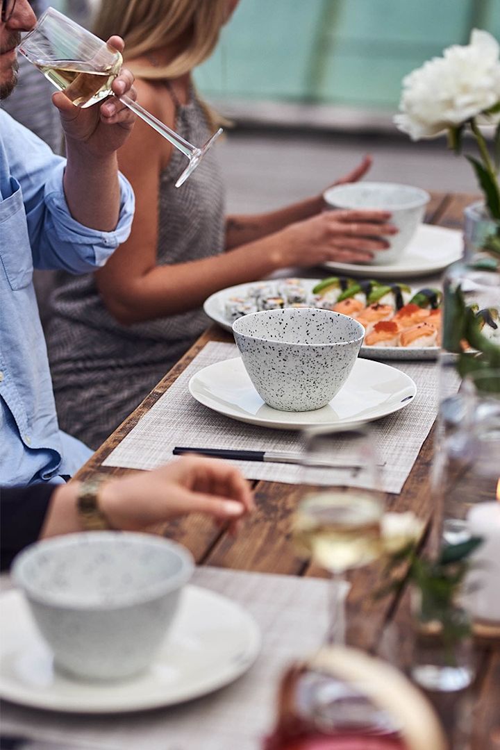 En sommarfest med vitt porslin från Arabia där sällskapet avnjuter en avslappnad middag helt enligt hygge principer. 