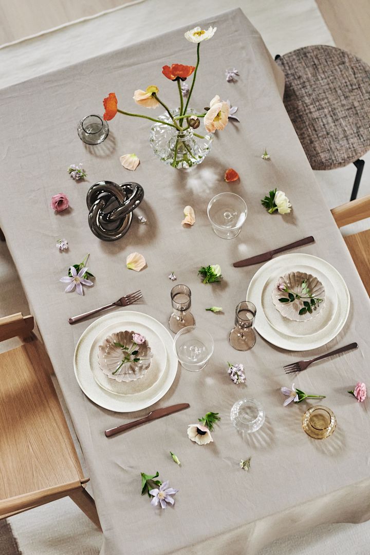 Skapa vackra festdukningar genom stilrent porslin från By On, champagneglas från Ferm living och Blomus med vacker blomster som dekoration.