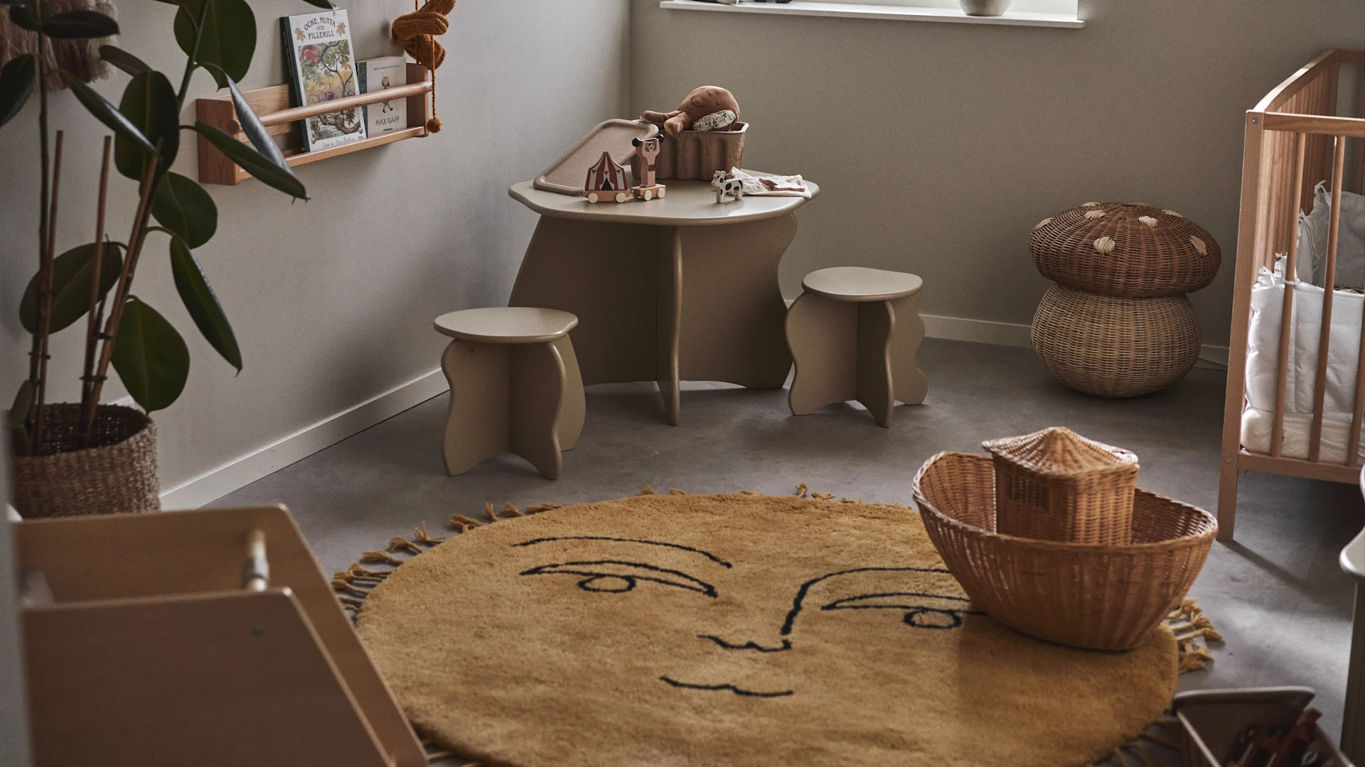Att lägga en mjuk, stor matta i rummets mitt skapar en mysig och generös lekyta när du ska inreda barnrum. Här den sol-formade mattan Sun från Ferm Living i barnrum med bord, pallar och spjälsäng.