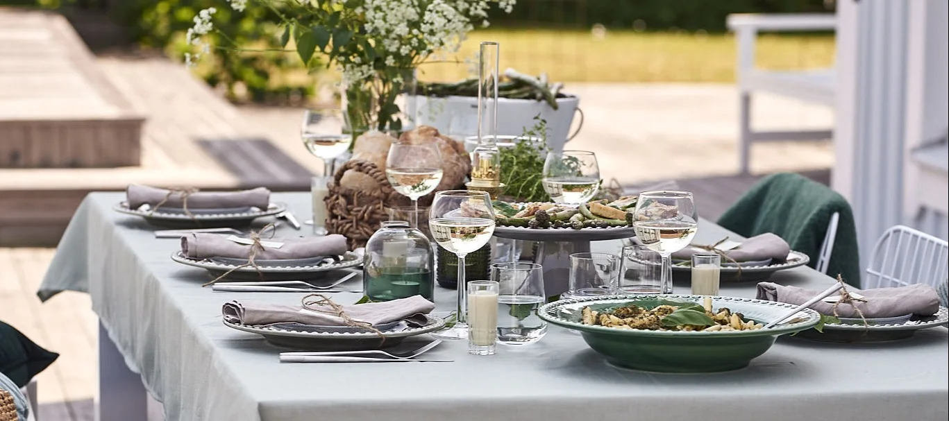 En sommardukning med tema grönt står uppdukat på verandan för härlig trädgårdsfest.