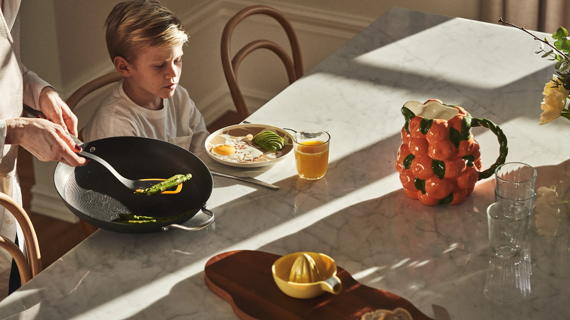 Duka upp för lyxig helgfrukost, här uppdukat vid marmorbord med stekt ägg och avokado, färskpressad juice och skärbräda med nybakat bröd.