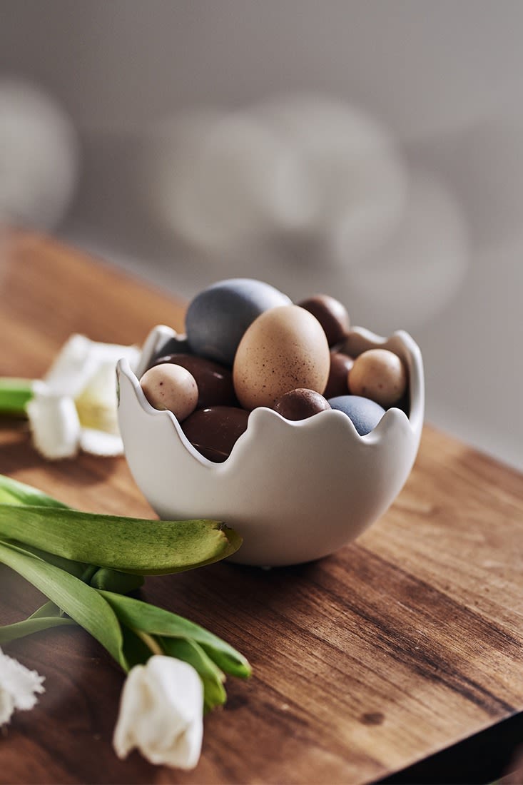 En skål från DBKD i äggform fylld med färgade ägg, naturliga ägg och godisägg. 