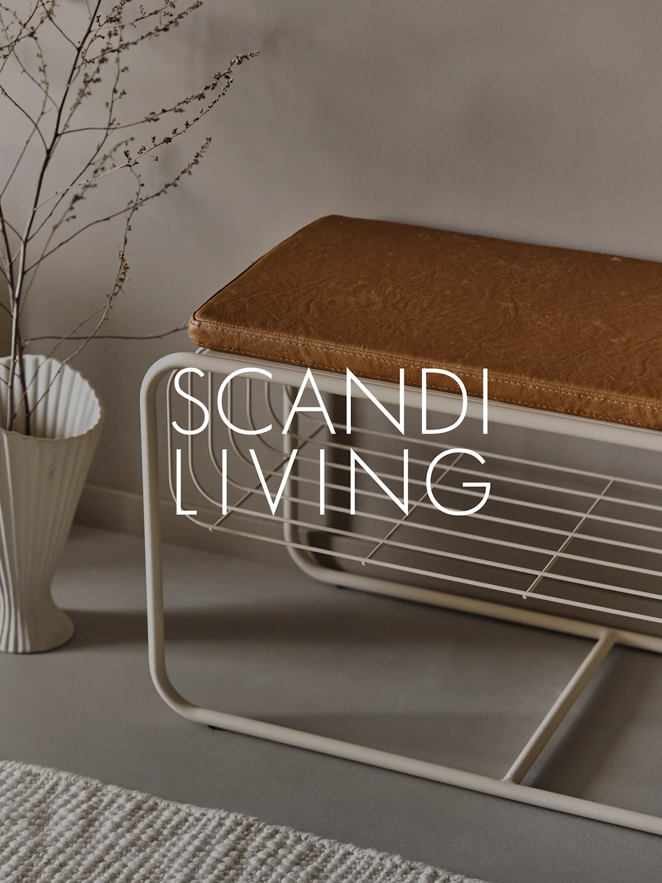 Hallbänk med brun dyna, skohylla, vit räfflad vas med grenar och texten 'SCANDI LIVING'.