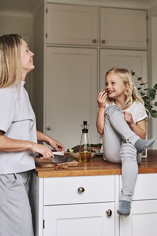 Ett kök inrett i sann skandinavisk stil med bänkskiva i trä och vita köksluckor bjuder in till middagsförberedelser. 