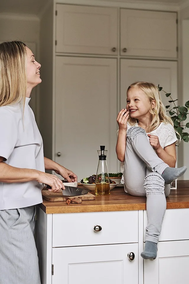 Ett kök inrett i sann skandinavisk stil med bänkskiva i trä och vita köksluckor bjuder in till middagsförberedelser.