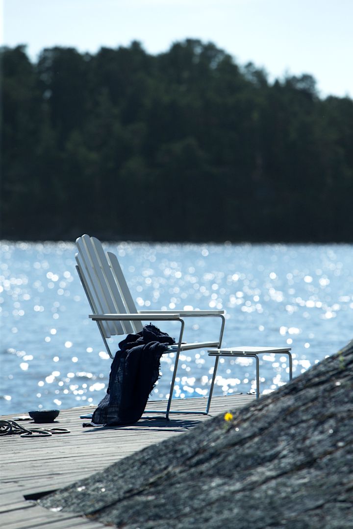 Lär känna Grythyttan Stålmöbler, här fåtölj i vitt vid havet.
