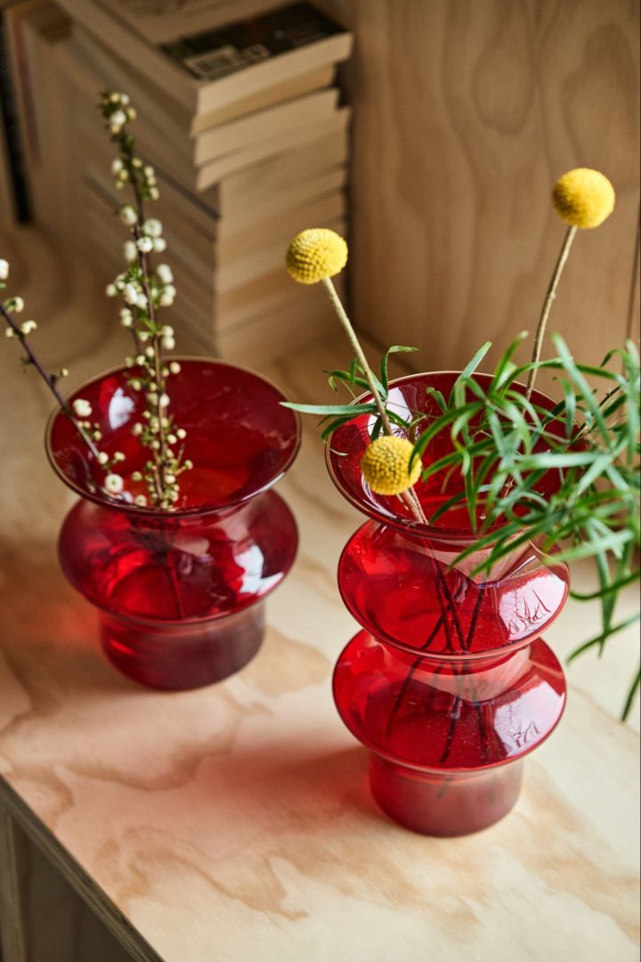 Röda Pagod-vaser från Kosta Boda med gula och gröna blommor i. 