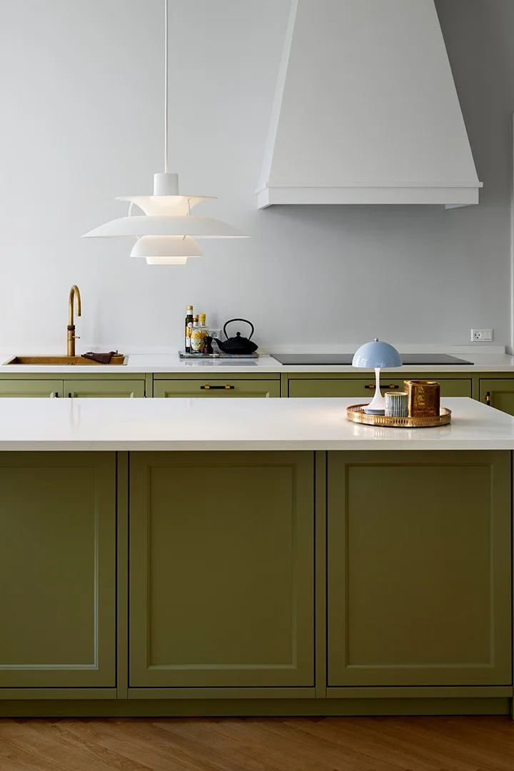 Ett grönt kök med en PH 5 pendel hängande över en köksö. 