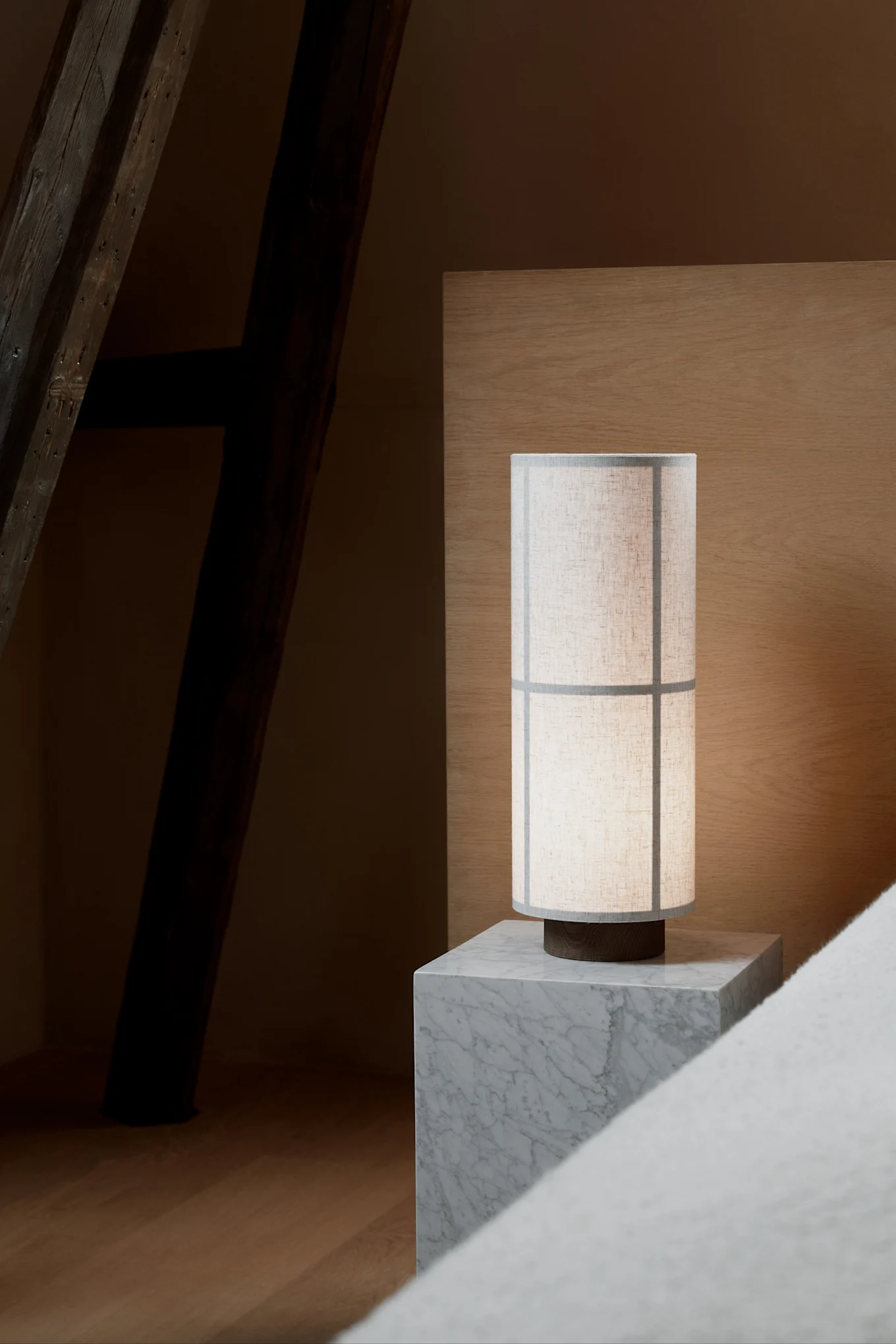 På ett grått nattduksbord i marmor står Hashira table lamp från Audo Copenhagen, formgiven i en stil som för tankarna till Japandi.