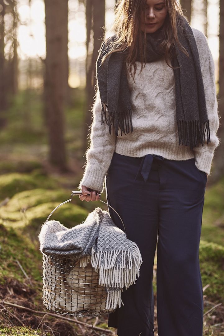 Korbo korg fylld med ullplädar bärs fram till glöggminglet i skogen. 